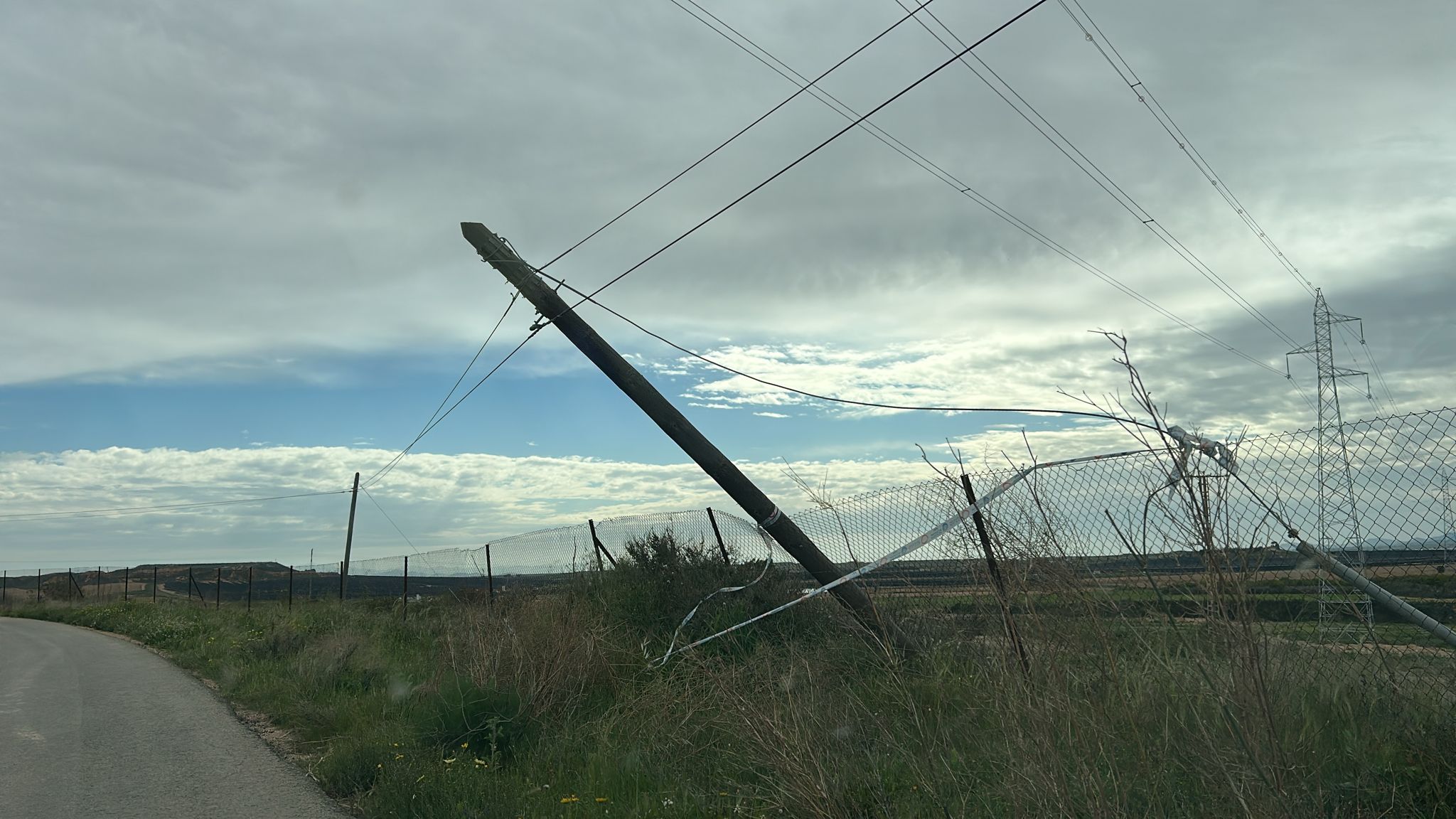 Un poste de cableado volcado y apunto de caer sobre la carretera en las casas del Maestro, Gea y Truyols
